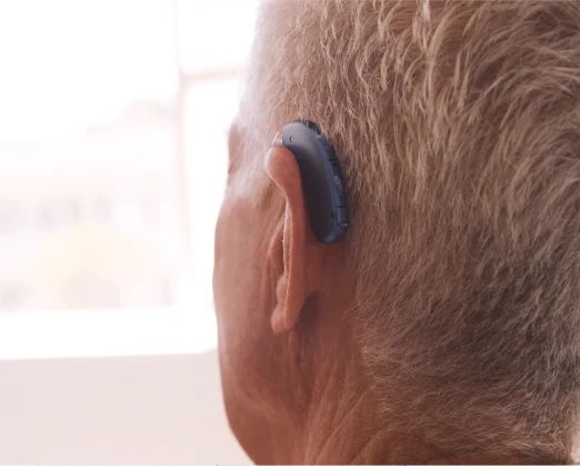 Persona utilizando un audífono clínico detrás de la oreja